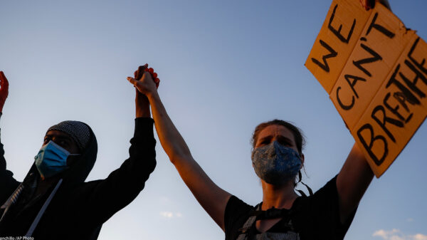 A man and a woman holding a sign reading "We can't Breathe"