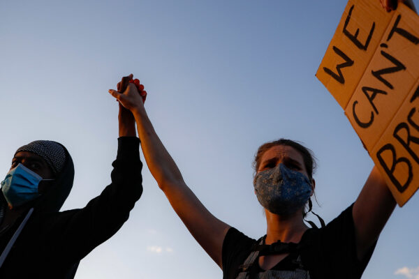 A man and a woman holding a sign reading "We can't Breathe"
