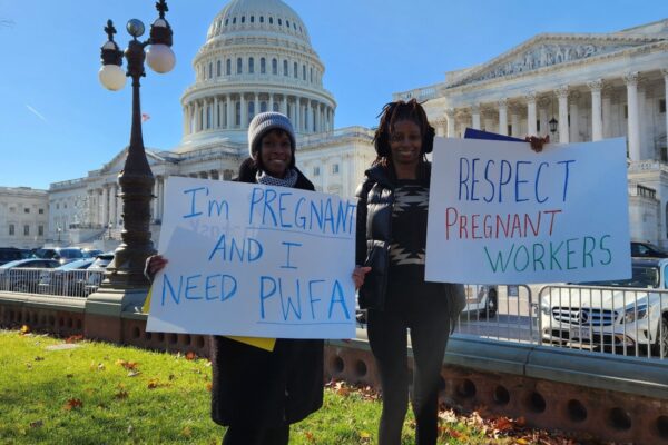 Two women holding signs outside of the US Capitol advocating for the Pregnant Workers Fairness Act
