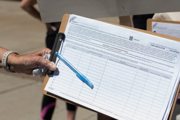 A canvasser gathers a petition signature.