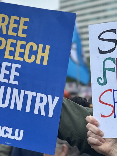 ACLU poster with FREE SPEECH, FREE COUNTRY written in yellow and white letters on blue background.