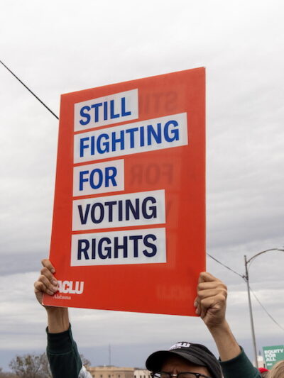 ACLU sign, blue text on white and red background reading, "Still Fighting for Voting Rights."