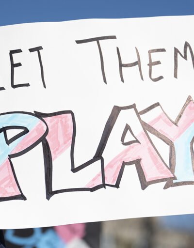 Sign reading Let Them Play in pink, blue and white colors.