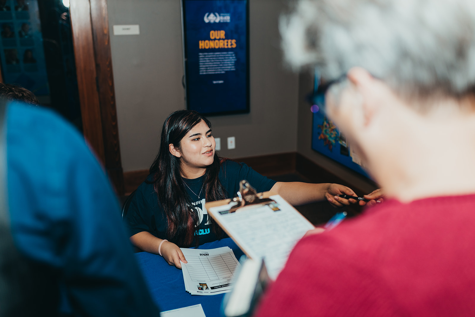 ACLU of Arkansas volunteer Sofia checks people in for the Evening with Deborah Archer event.