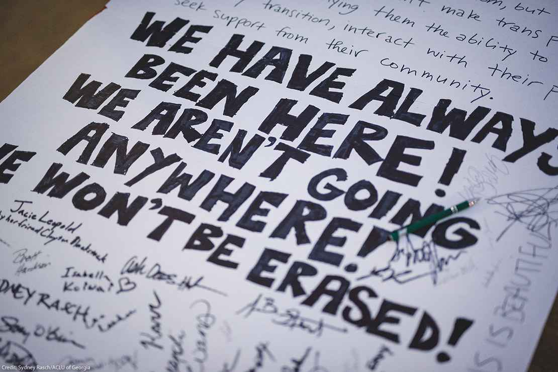 A demonstration poster that reads “We Have Always Been Here! We Aren’t Going Anywhere! We Won’t Be Erased.”