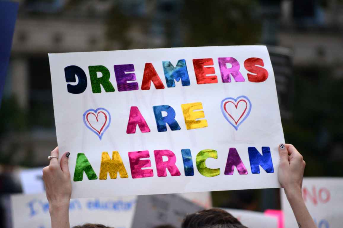 White background with rainbow letters. Text: Dreamers are American with two hearts.