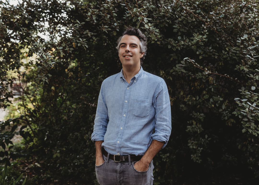 White male with gray hair wearing a denim shirt with jeans and black belt. The man has his hands in his pockets and is smiling. Text on the image reads, "Welcome Our New Legal Director, John C. Williams! "