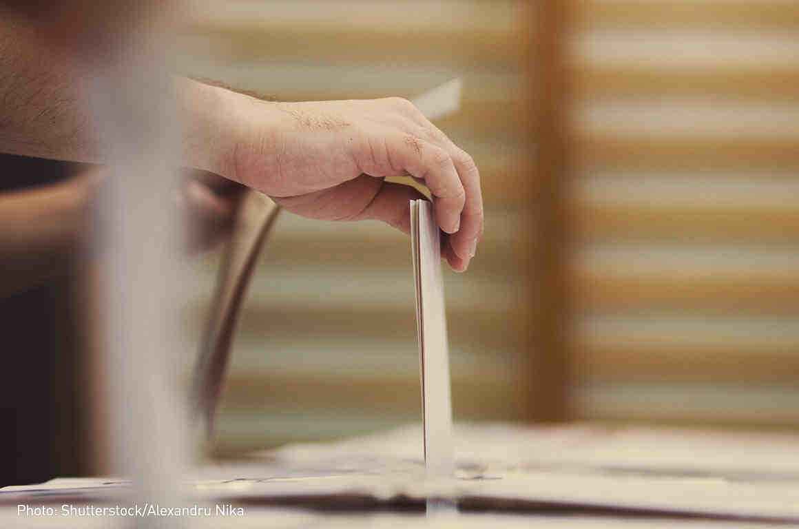 Photo of voter putting a ballot in a ballot box