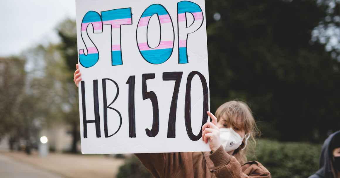 A woman holds a rally sign that reads "Stop HB1570"