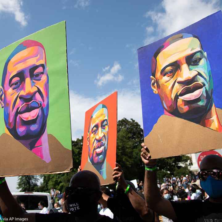 Protesters holding signs depicting George Floyd.